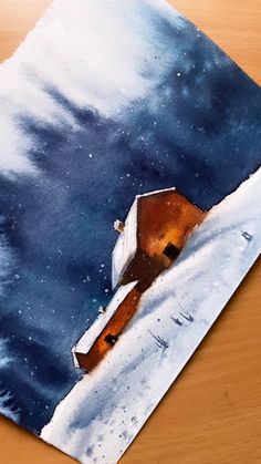 a painting of a house in the snow on a wooden table with blue sky and white clouds