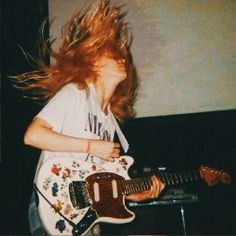 a woman with red hair playing an electric guitar