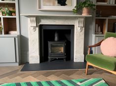 a living room with a green chair and a wood burning stove in it's center