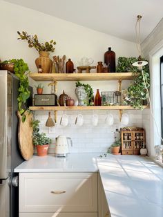 a kitchen filled with lots of pots and pans on top of shelves next to a refrigerator