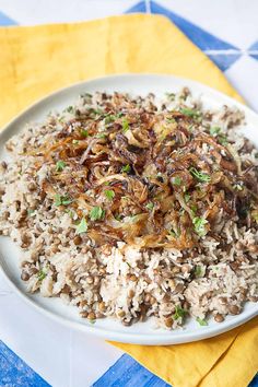 a white plate topped with rice and mushrooms on top of a blue and yellow napkin