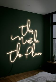 this must be the plan neon sign on wall next to bed in dark green room