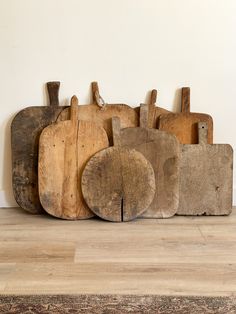 several wooden cutting boards are stacked on top of each other in front of a white wall