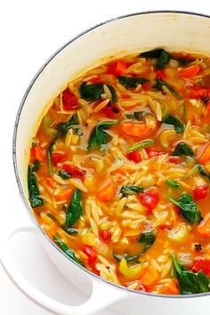 a white pot filled with pasta and vegetables