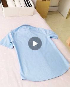 a baby laying on top of a bed with a blue shirt on it's back