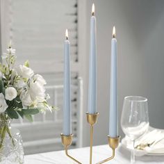 three candles on a table with white flowers