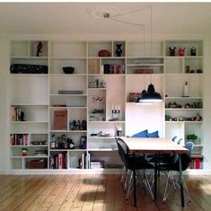 a dining room table and chairs in front of a bookshelf filled with shelves