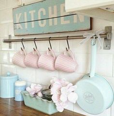 a kitchen with pink flowers hanging from the hooks on the wall and other utensils