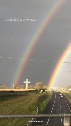 two rainbows are in the sky above a road with cars on it and a sign that says jesus is the only way