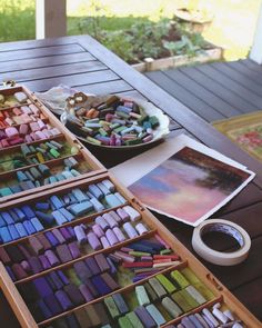 there are many different colored crayons in the trays on the table next to each other