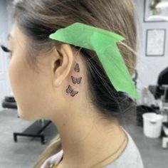 a woman with a tattoo on her left ear has a green leaf in the shape of a butterfly