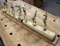 several brass figurines are lined up on a wooden table with holes in it