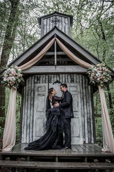 a man and woman standing on top of a wooden platform in front of a building