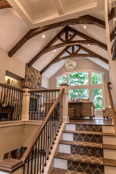 a staircase leading up to a large window in a home with stone walls and wood beams