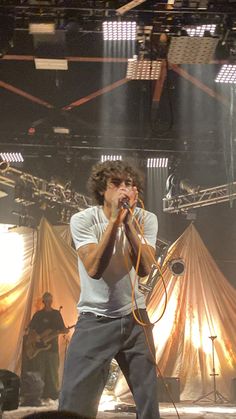 a man standing on top of a stage holding a microphone in his hand and singing