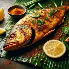 a fish is sitting on top of a leafy table next to lemons and spices