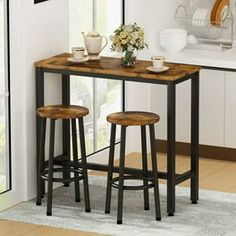 a kitchen table with two stools in front of it and flowers on the counter