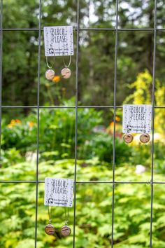 three pieces of metal are hanging on the fence in front of some plants and flowers