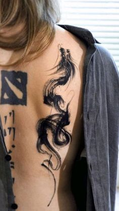 the back of a woman's body with tattoos on it