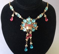 "Old gold tone, vibrant jewel tone rhinestone necklace.  Bohemian designs were very colorful and varied. Some pendants had more, others, less, glass stones.  This beautiful Czech or Austrian from the 1920's has more gems and they are placed in attractive patterns of deep pink, blue and clear.  Some are prong set and others are bezel set.   Gorgeous!  Minor wear after 100 years.  Some of the foiled backing is peeling. (Photo # 8) The blemishes don't seem to interfere with the beauty of the piece.  There is some staining on the brass back plate, also.  Please enlarge and look carefully.  All gems are intact.  Nice gilt brass wheat chain.  Unusual craftsmanship.  The extra loops are apparently not for additional gems.  Dimensional.  About 3/4\" high.  Necklace is 17 1/2\" long  Pendant: 1 7/8 Costume Jewelry Rhinestone Pendant Necklace, Vintage Multi-stone Pendant Necklace, Vintage Gold Multi-stone Necklace, Jeweled Costume Jewelry Necklaces For Evening, Vintage Rhinestone Pendant Jewelry, Vintage Multicolor Rhinestone Jewelry, Collectible Costume Jewelry With Jewels, Antique Jeweled Necklaces For Party, Costume Jewelry Rhinestone Necklace