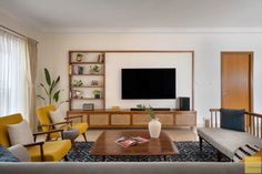 a living room filled with furniture and a flat screen tv mounted on a wall above a wooden coffee table