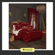 a bed with red comforter and pillows in a room next to a christmas tree