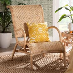 a wicker chair with a yellow pillow in front of a potted plant on a table