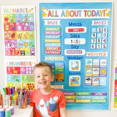 a young boy standing in front of a bulletin board with calendars and markers on it