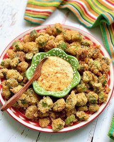 a plate full of fried vegetables with a dipping sauce on the side and colorful napkins in the background