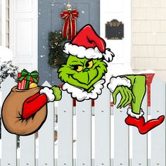 the grinch is holding a sack of presents in front of a white picket fence