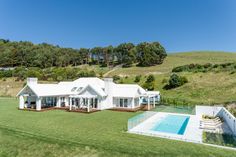 an aerial view of a house with a swimming pool in the foreground and lush green hills in the background