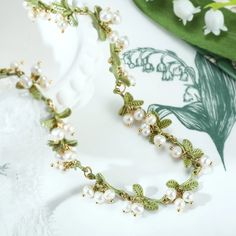 On a chain painted to look like a green stem, pieces of green leaves and clusters of white lilies of the valley are hanging regularly, refined and elegant. As the lily of the valley represents happiness and pure love, it is the ideal necklace to give to someone or to treat yourself as a gift with good wish. DETAILS Pl Lily Of The Valley Jewelry, Lily Of The Valley Bouquet, Lilies Of The Valley, Peach Earrings, Cat Pendant Necklace, Mermaid Pendant, Simple Gift Wrapping, Horses Pendant, Purple Grapes