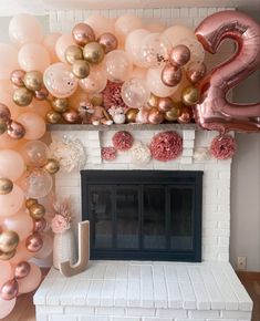 a fireplace decorated with pink and gold balloons