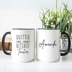 two coffee mugs sitting on top of a table next to a vase with flowers