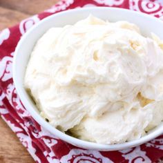 a white bowl filled with whipped cream on top of a red and white towel