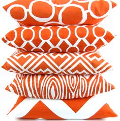 four orange and white pillows stacked on top of each other in front of a white background