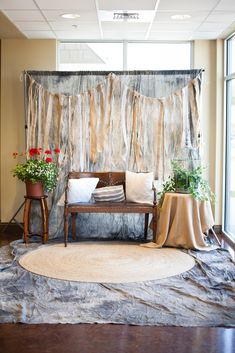 a room with a couch, table and flowers on the floor in front of a curtain