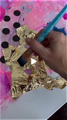 someone is painting gold foil with a blue brush