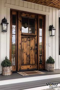 a wooden door sitting on the side of a white house next to potted plants