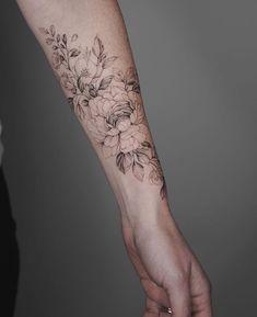 a woman's arm with flowers on it and a hand holding the other arm