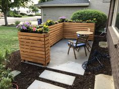 a wooden planter sitting on top of a patio next to a table and chairs