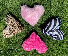 four stuffed animals arranged in the shape of a heart on green grass with zebra print and pink fur