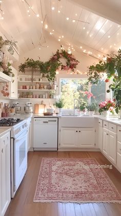 a kitchen with white cabinets and lots of plants hanging from the ceiling over the stove