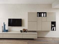 a living room with white furniture and a flat screen tv mounted on the wall above it