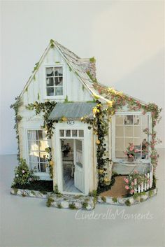 a doll house is decorated with flowers and greenery on the front door, windows, and porch