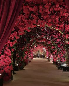 an archway covered in red flowers and greenery