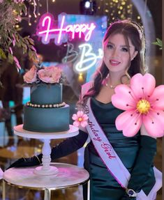 a woman is holding a cake with flowers on it in front of a happy birthday sign