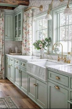 a large kitchen with green cabinets and marble counter tops, gold faucets and brass fixtures