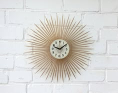 a white brick wall with a gold clock on it and the time is 11 00