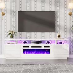 an entertainment center with a large television mounted on it's wall and purple flames in the fireplace